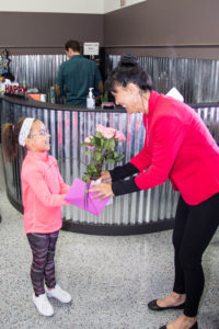 Owner Sherry Blaha getting Flowers from a student at the Grand Opening
